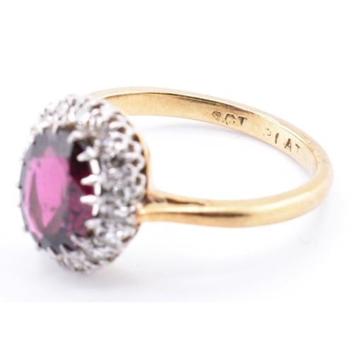 31A - An 18ct gold and platinum garnet and diamond cluster ring. The 18ct yellow gold ring set with a claw... 