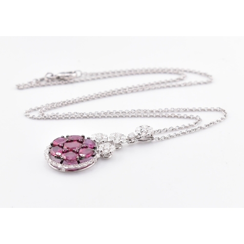 32 - An 18ct white gold, ruby and diamond pendant. The 18ct white gold necklace pendant having seven oval... 