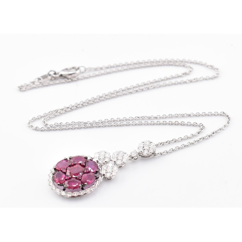 32 - An 18ct white gold, ruby and diamond pendant. The 18ct white gold necklace pendant having seven oval... 