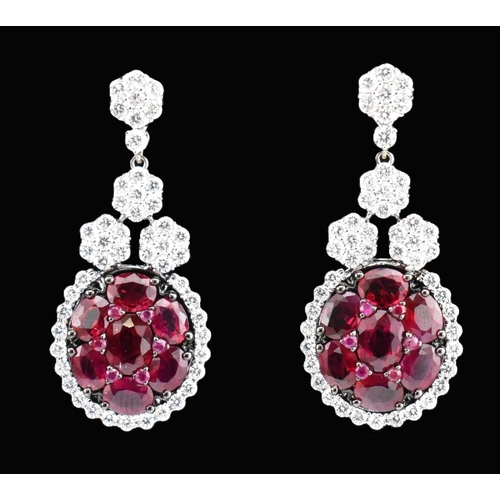 33 - A pair of 18ct gold ruby and diamond pendant earrings. The 18ct white gold earrings having a cluster... 