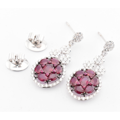 33 - A pair of 18ct gold ruby and diamond pendant earrings. The 18ct white gold earrings having a cluster... 