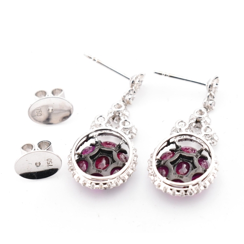 33 - A pair of 18ct gold ruby and diamond pendant earrings. The 18ct white gold earrings having a cluster... 