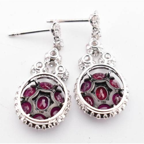 33 - A pair of 18ct gold ruby and diamond pendant earrings. The 18ct white gold earrings having a cluster... 