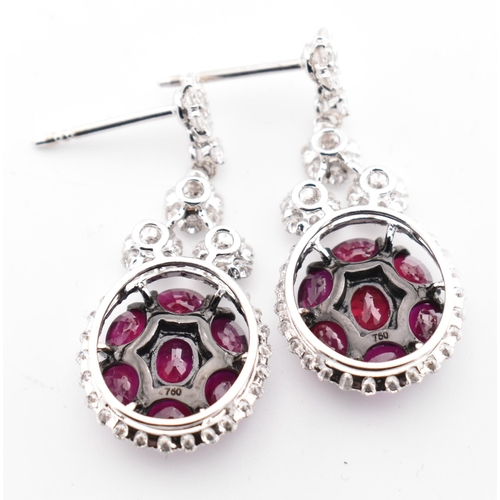 33 - A pair of 18ct gold ruby and diamond pendant earrings. The 18ct white gold earrings having a cluster... 