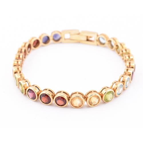 35 - An 18ct gold multi gem set tennis bracelet. The bracelet having twenty-five bezel set gems including... 