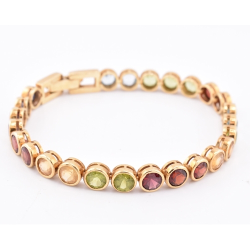 35 - An 18ct gold multi gem set tennis bracelet. The bracelet having twenty-five bezel set gems including... 