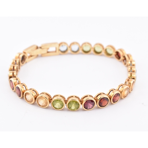 35 - An 18ct gold multi gem set tennis bracelet. The bracelet having twenty-five bezel set gems including... 