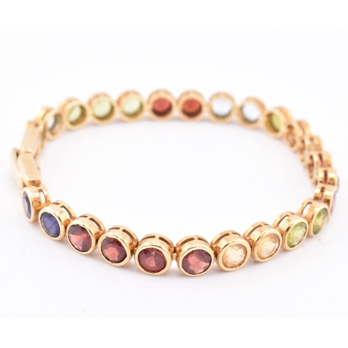 35 - An 18ct gold multi gem set tennis bracelet. The bracelet having twenty-five bezel set gems including... 