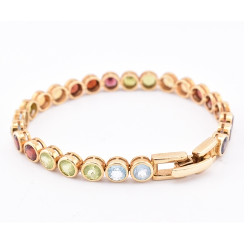 35 - An 18ct gold multi gem set tennis bracelet. The bracelet having twenty-five bezel set gems including... 