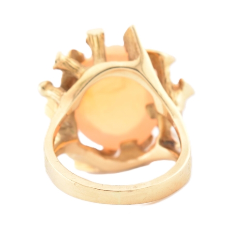 37 - An 18ct gold Mexican opal ring. The ring set with a high opal cabochon set amongst naturalistic fron... 