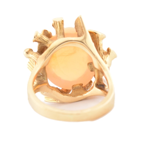 37 - An 18ct gold Mexican opal ring. The ring set with a high opal cabochon set amongst naturalistic fron... 