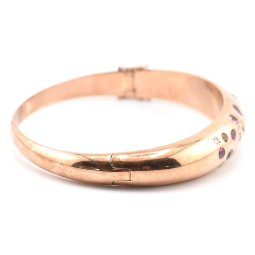 49a - A hallmarked 9ct rose gold sapphire, diamond gem set bombe bangle. The hinged bangle set with diamon... 