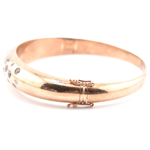 49a - A hallmarked 9ct rose gold sapphire, diamond gem set bombe bangle. The hinged bangle set with diamon... 