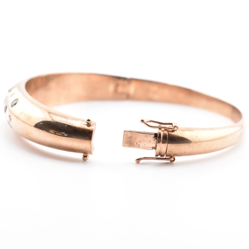 49a - A hallmarked 9ct rose gold sapphire, diamond gem set bombe bangle. The hinged bangle set with diamon... 