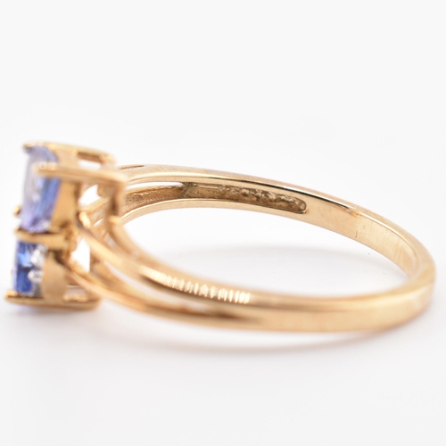 53 - A hallmarked 9ct tanzanite and diamond crossover ring. The 9ct yellow gold ring set with two trillia... 