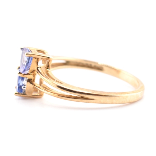 53 - A hallmarked 9ct tanzanite and diamond crossover ring. The 9ct yellow gold ring set with two trillia... 