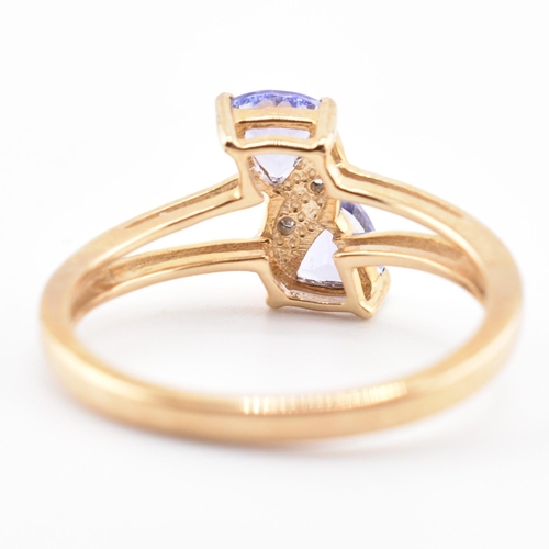 53 - A hallmarked 9ct tanzanite and diamond crossover ring. The 9ct yellow gold ring set with two trillia... 