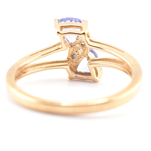 53 - A hallmarked 9ct tanzanite and diamond crossover ring. The 9ct yellow gold ring set with two trillia... 