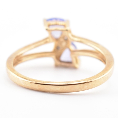 53 - A hallmarked 9ct tanzanite and diamond crossover ring. The 9ct yellow gold ring set with two trillia... 