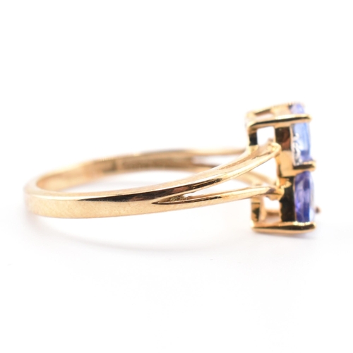 53 - A hallmarked 9ct tanzanite and diamond crossover ring. The 9ct yellow gold ring set with two trillia... 