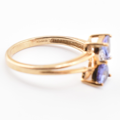 53 - A hallmarked 9ct tanzanite and diamond crossover ring. The 9ct yellow gold ring set with two trillia... 