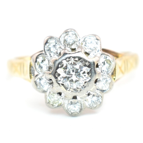 53a - A hallmarked 18 ct gold and diamond flower cluster ring. The ring set with a central round brilliant... 