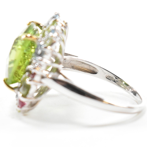 56a - A hallmarked 18ct gold peridot and gem set cluster ring. The ring set with a cushion cut peridot fra... 