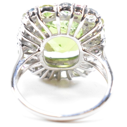 56a - A hallmarked 18ct gold peridot and gem set cluster ring. The ring set with a cushion cut peridot fra... 