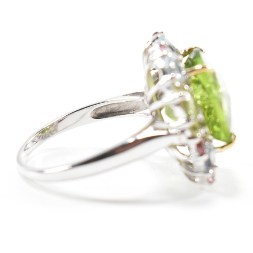 56a - A hallmarked 18ct gold peridot and gem set cluster ring. The ring set with a cushion cut peridot fra... 