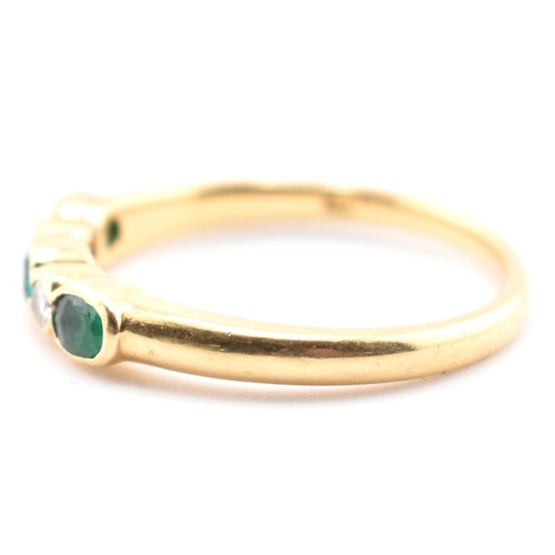 58a - A hallmarked 18ct gold emerald and diamond five-stone ring. The ring having three oval cut emeralds ... 