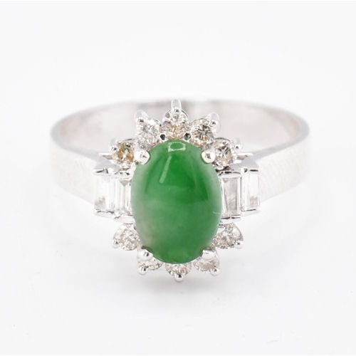 60 - An 18ct white gold jade and diamond halo ring. The 18ct white gold ring set with a central oval jade... 