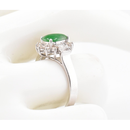 60 - An 18ct white gold jade and diamond halo ring. The 18ct white gold ring set with a central oval jade... 