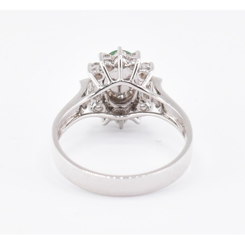 60 - An 18ct white gold jade and diamond halo ring. The 18ct white gold ring set with a central oval jade... 