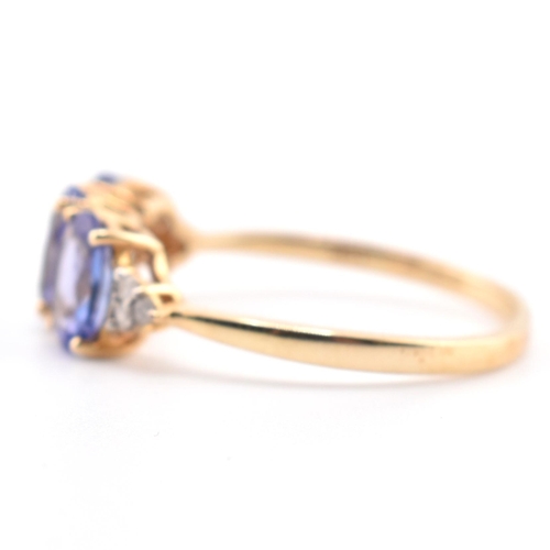 63 - A hallmarked 9ct gold tanzanite and diamond ring. The 9ct yellow gold ring set with three oval cut t... 