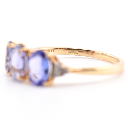 63 - A hallmarked 9ct gold tanzanite and diamond ring. The 9ct yellow gold ring set with three oval cut t... 