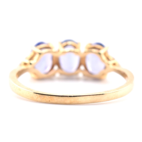 63 - A hallmarked 9ct gold tanzanite and diamond ring. The 9ct yellow gold ring set with three oval cut t... 