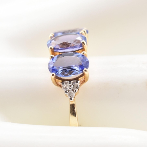 63 - A hallmarked 9ct gold tanzanite and diamond ring. The 9ct yellow gold ring set with three oval cut t... 