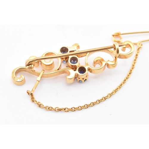 66 - A 15ct gold and sapphire brooch pin. The 15ct yellow gold brooch pin of swirling form having three r... 