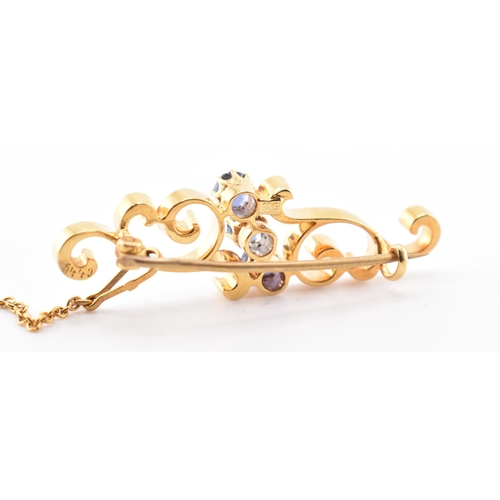 66 - A 15ct gold and sapphire brooch pin. The 15ct yellow gold brooch pin of swirling form having three r... 