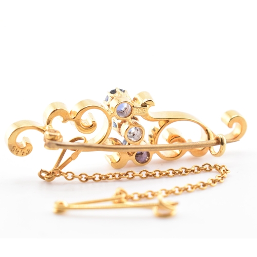 66 - A 15ct gold and sapphire brooch pin. The 15ct yellow gold brooch pin of swirling form having three r... 