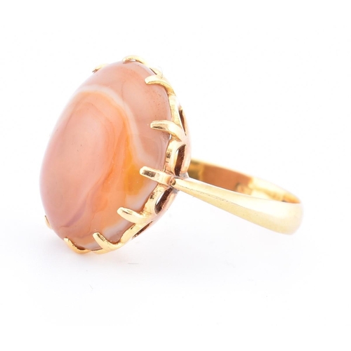 67 - A gold and agate ring. The ring having a claw set round agate cabochon to tapered shoulders and poli... 