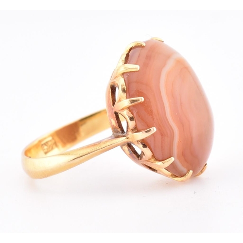 67 - A gold and agate ring. The ring having a claw set round agate cabochon to tapered shoulders and poli... 