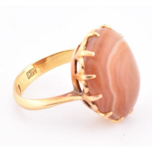 67 - A gold and agate ring. The ring having a claw set round agate cabochon to tapered shoulders and poli... 