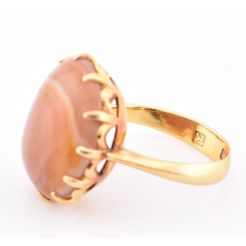 67 - A gold and agate ring. The ring having a claw set round agate cabochon to tapered shoulders and poli... 