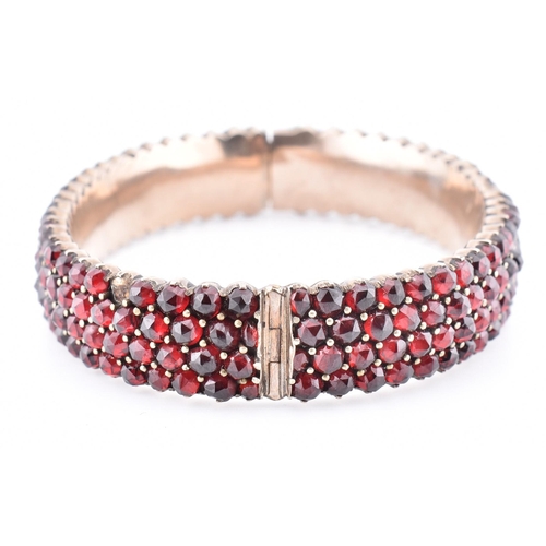 74 - A collection of Bohemian garnet jewellery. The lot to include a garnet set hinged bangle with concea... 