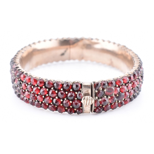 74 - A collection of Bohemian garnet jewellery. The lot to include a garnet set hinged bangle with concea... 