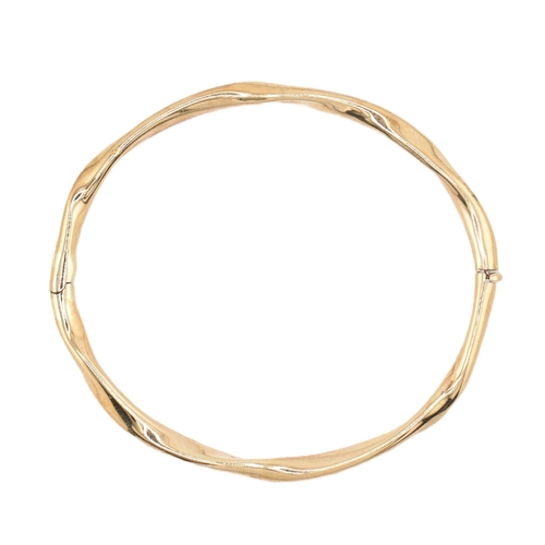 79 - A hallmarked 9ct gold hinged bangle cased. The 9ct yellow gold bangle having a twisted design with h... 