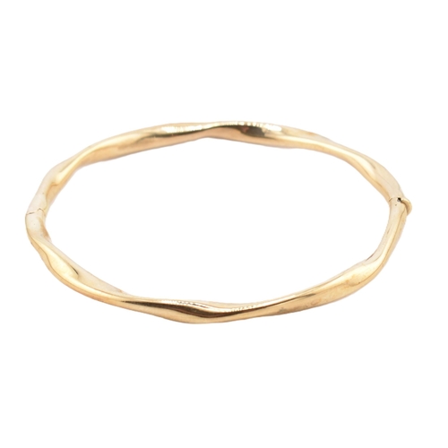 79 - A hallmarked 9ct gold hinged bangle cased. The 9ct yellow gold bangle having a twisted design with h... 