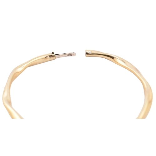 79 - A hallmarked 9ct gold hinged bangle cased. The 9ct yellow gold bangle having a twisted design with h... 