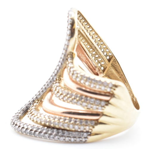 83 - A 9ct bi-colour gold and CZ swirl ring. The 9ct gold swirl ring having four yellow gold rows of pave... 